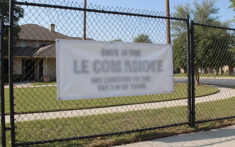 Leasing banner on a fence outside a new apartment community, no readable text